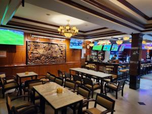 芭堤雅市中心The Pattaya Sports Hub的一间带桌椅和电视的餐厅