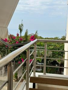 希马拉ELÉA Guesthouse himare的拥有粉红色花卉和海洋的阳台