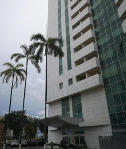 巴西利亚Hotel Lider à 1km da Esplanada dos Ministérios的一座高大的建筑,前面有棕榈树