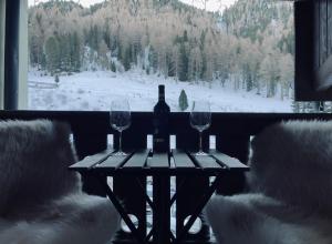 泰塞罗Dolomiti Haus - Immerso nelle Dolomiti的一张桌子,上面放着一瓶葡萄酒和两杯酒