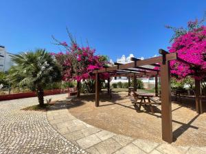 塔维拉Taste Tavira (by Annick) fully equipped apartment, tastefully decorated, perfect location and free parkingric center of the city of Tavira.的一个带野餐桌和粉红色鲜花的凉亭