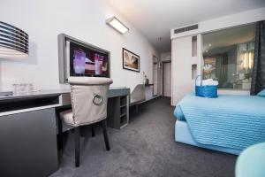罗维尼阿鲁宾努酒店的一间卧室配有一张床和一张书桌及电视