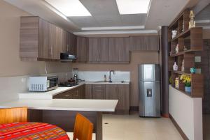 AtuntaquiTEYFA Hospedaje - Edificio的厨房配有木制橱柜和不锈钢冰箱。