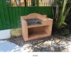 曼萨尼约Gran casa con alberca en playa的绿色栅栏前的木烤架