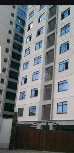 内罗毕JVcribstudios-Ndemi gardens apartments的一座高大的白色建筑,有许多窗户