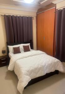 OgbojoEden Court Luxe的卧室配有带窗帘的大型白色床