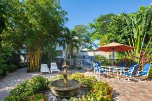 基韦斯特Old Town Garden Villas - Andros Suite的花园内的喷泉,花园内设有椅子和遮阳伞