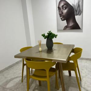 卡塔赫纳Apartamentos San José的餐桌,带黄色椅子和花瓶