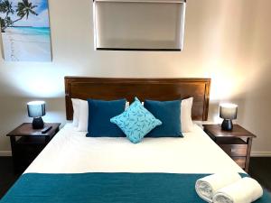洛坎普顿City Ville Apartments and Motel的一间卧室配有一张带蓝色和白色枕头的床