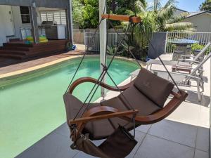 麦夸里港Luxury oasis resort Pet friendly apartment with private pool and spa的摆在游泳池旁的摇摆椅