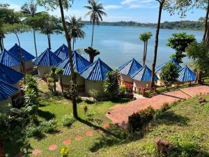 麦岛麦岛布里茅屋自然度假酒店的水边的一排蓝色帐篷