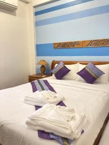 清迈维瑞雅别墅酒店的一间卧室配有一张带白色床单和紫色枕头的床