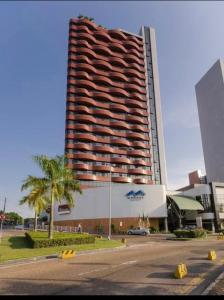 马瑙斯Flat Manaus Hotéis Millenniun的一座高大的建筑,前面有一棵棕榈树