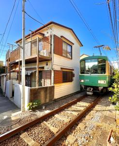 镰仓市江ノ電の線路沿いにある宿【film koshigoe】的绿色火车停在大楼前