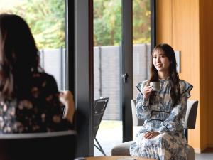胜浦市Kumano-bettei Nakanoshima的坐在椅子上拿着咖啡的女人
