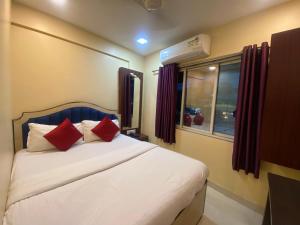 孟买Hotel Royal Grand - Near Mumbai International Airport的一间卧室配有一张带红色枕头的床和一扇窗户