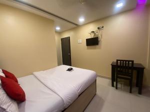 孟买Hotel Royal Grand - Near Mumbai International Airport的卧室配有1张床、1张桌子和1把椅子