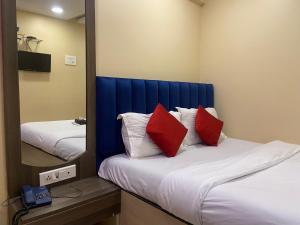 孟买Hotel Royal Grand - Near Mumbai International Airport的一间卧室配有两张带红色枕头和镜子的床