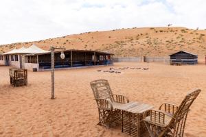 Al WāşilSand Delight Camp的沙漠中的海滩和建筑
