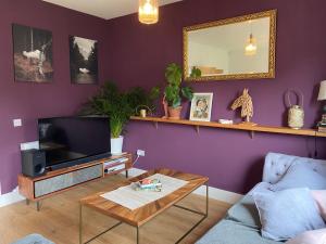 邦尼里格Modern Home Near Edinburgh City的客厅拥有紫色的墙壁,配有电视和桌子
