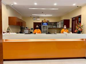 曼谷卡里普佐曼谷酒店的两人穿着橙色衬衫站在柜台后