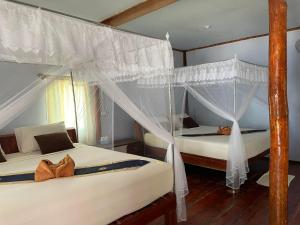 俊穆岛俊穆岛瑞莱克斯海滩旅馆的一间卧室配有两张带蚊帐的床