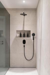 萨尔茨堡Altstadt-App. Domblick!的浴室设有淋浴间,架子上装有四瓶水