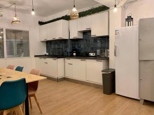 马德里Boga Hostel的厨房配有白色橱柜、桌子和冰箱。