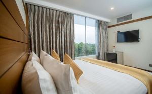 拉杰沙希Hotel X Rajshahi的一间卧室设有一张大床和大窗户