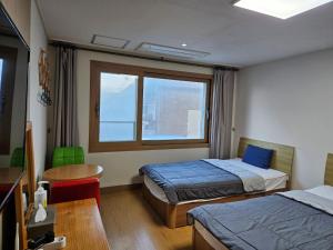 济州市萨姆达旅舍的客房设有两张床、一张桌子和一扇窗户。