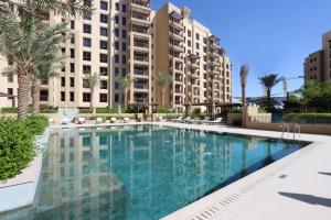 迪拜Livbnb - 2BR close to Souk Mall and Burj Al Arab的一座棕榈树和建筑游泳池