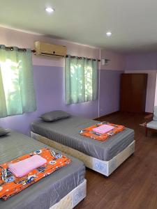 Ban Cha-omAmano green resort的紫色墙壁客房的两张床