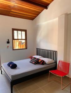 朱奎Hostel Txai Juquehy Suítes的一间卧室配有一张床和一张红色椅子