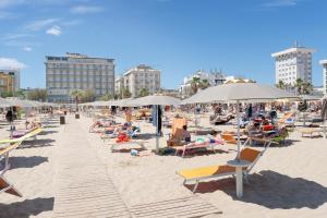 里米尼Hotel Centrale Miramare的一群人坐在海滩上,拿着遮阳伞