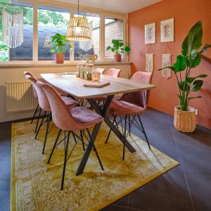 拉纳肯Bungalow AMNIS的用餐室配有木桌和粉红色椅子