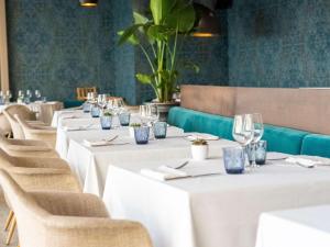 曼德琉-拉纳普勒铂尔曼戛纳曼德里亚皇家赌场酒店的餐厅的一排桌子,上面有白色的桌布