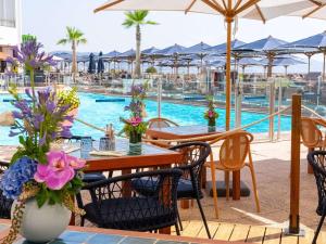 曼德琉-拉纳普勒铂尔曼戛纳曼德里亚皇家赌场酒店的一个带桌椅的庭院和一个游泳池