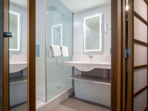 维也纳维也纳诺富特酒店的一间带两个盥洗盆和淋浴的浴室