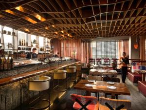 曼谷VIE Hotel Bangkok, MGallery的餐厅设有酒吧,配有凳子和桌子