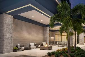 奥兰多Home2 Suites Orlando Southeast Nona的大堂设有桌椅和棕榈树