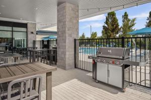 奥兰多Hampton Inn Orlando Southeast Nona的露台上的烧烤架,设有桌子和游泳池