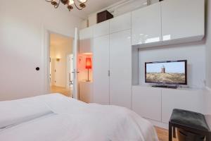 韦斯特兰Die Schlosserei的白色的卧室设有床铺和墙上的电视