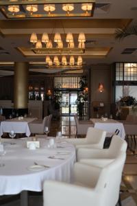 敖德萨卡多尔度假酒店的餐厅配有白色的桌椅和吊灯