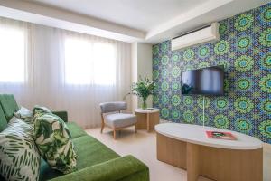 塞维利亚塞维利亚皮埃尔假日酒店的客厅配有绿色沙发和电视
