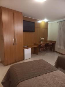 蓬塔格罗萨Barbur Center Hotel的一间卧室配有一张床和一张书桌及电视