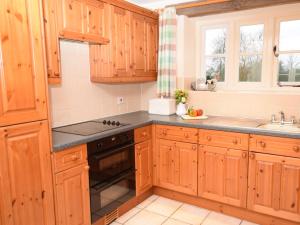 2 Bed in Cirencester CC094的厨房配有木制橱柜和炉灶烤箱。