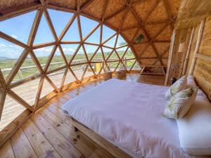 RobandaKuoom Serengeti的木制客房内的一张大床,设有大窗户