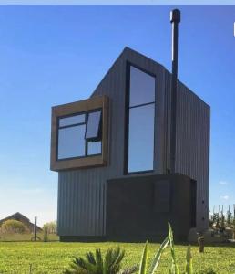 坎巴拉Tiny House Cambará的绿色田野上带两扇窗户的房子