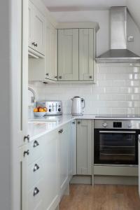 桑希尔Stableyard Apartment: Drumlanrig Castle的白色的厨房配有白色橱柜和炉灶。