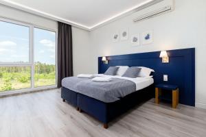 奥尔什丁Nowoczesne apartamenty Jezioro Ukiel Zatoka Miła Plaża Miejska的一间卧室设有蓝色的床和大窗户